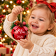 Child holding a personalized red Christmas jingle bell ornament